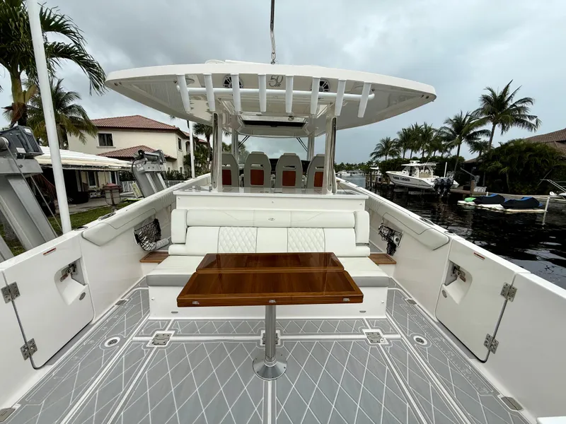 Slide: The Image of 2021 Regal 38 SAV boat with spacious deck, seating, and table, docked near waterfront homes. - 4
