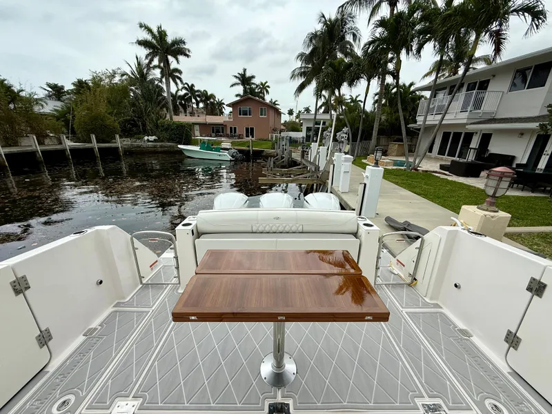 Slide: The Image of 2021 Regal 38 SAV boat docked, featuring a sleek deck and wooden table, surrounded by palm trees. - 7