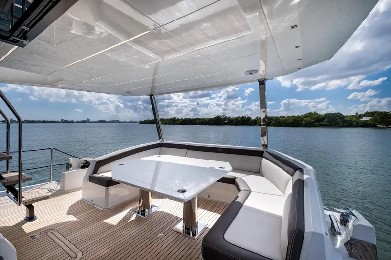 Slide: The Image of Luxurious 2020 Galeon 640 Fly yacht deck with seating and table, overlooking serene water. - 13