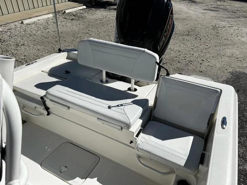 Slide: The Image of 2024 Skeeter SX230 boat seating area with white cushions and motor in background. - 16