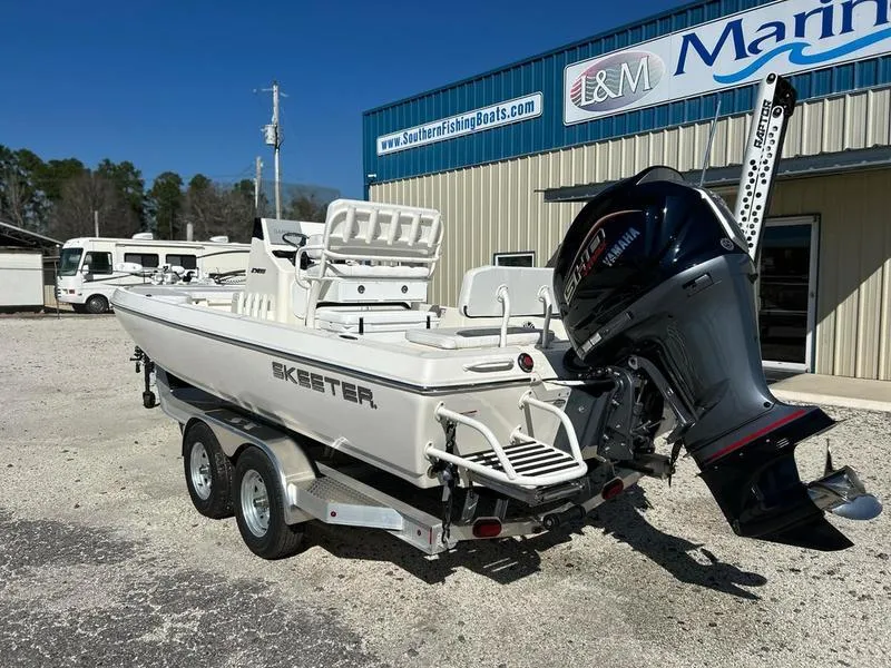 Slide: The Image of 2024 Skeeter SX230 boat on trailer, parked outside marine dealership. - 2