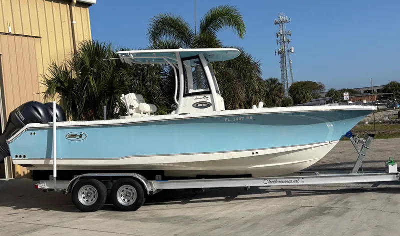 The Image of 2018 Sea Hunt Gamefish 25 boat on trailer, light blue hull, parked outdoors. - 1