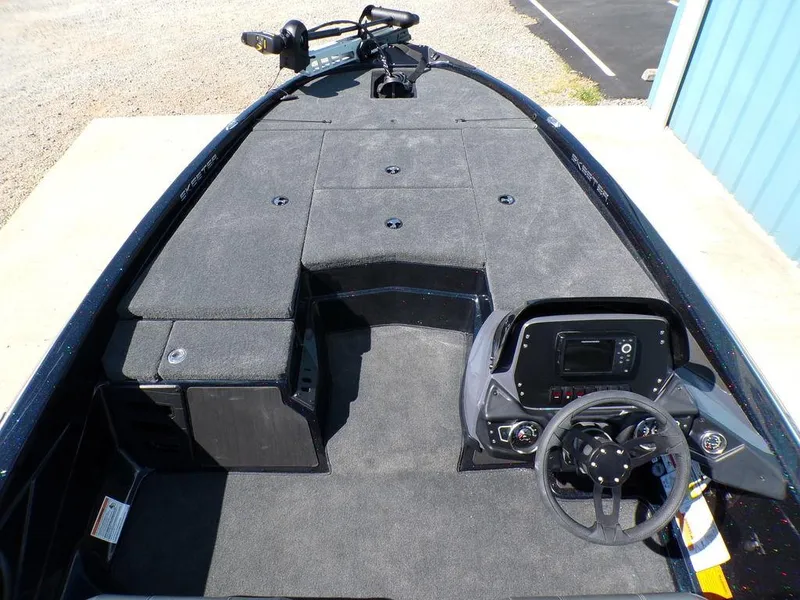 Slide: The Image of 2024 Skeeter ZX150 boat interior with steering console and carpeted deck. - 15