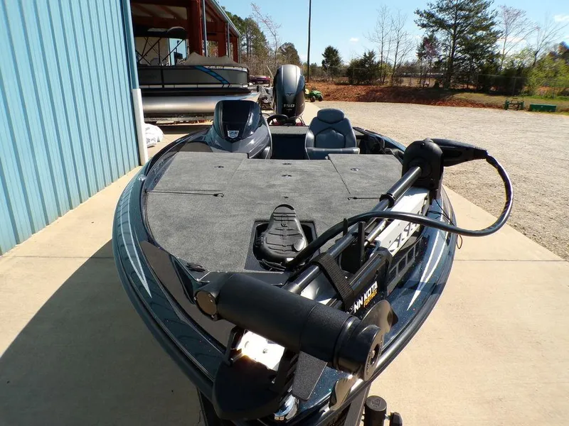 Slide: The Image of 2024 Skeeter ZX150 fishing boat with trolling motor, parked outdoors near a blue building. - 8