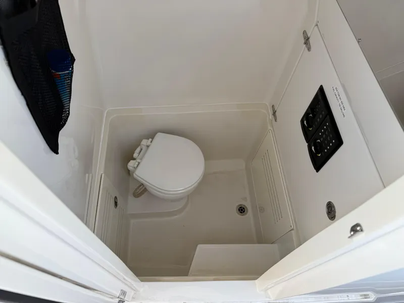 Slide: The Image of Compact bathroom in a 2016 Jupiter 26 boat, featuring a toilet and storage compartment. - 27
