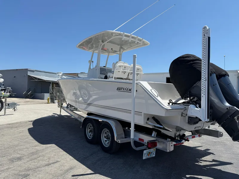 Slide: The Image of 2016 Jupiter 26 boat on trailer, parked outdoors under clear blue sky. - 30