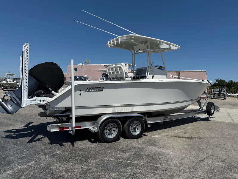 Slide: The Image of 2016 Jupiter 26 boat on trailer, parked outdoors under clear blue sky. - 32