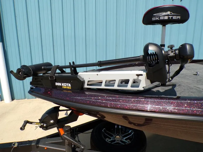 Slide: The Image of 2024 Skeeter ZX150 boat with Minn Kota Fortrex trolling motor, parked near a blue building. - 15