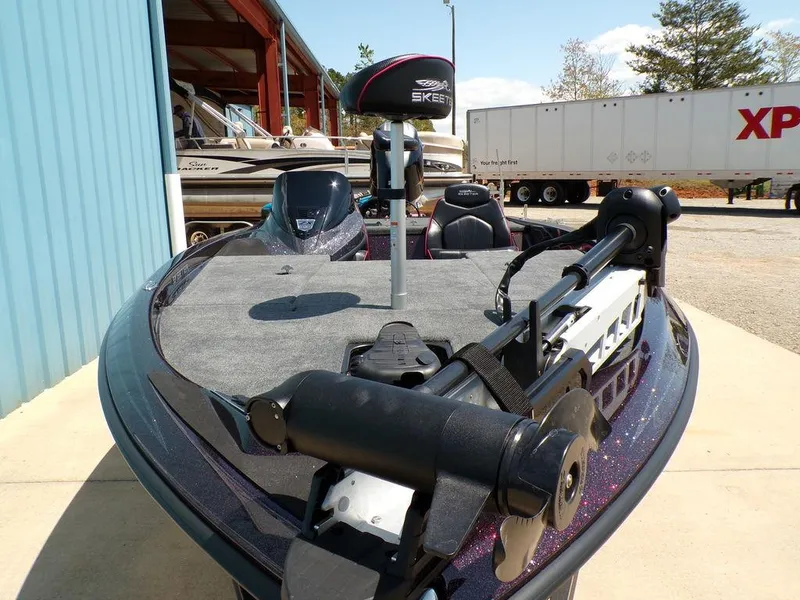 Slide: The Image of 2024 Skeeter ZX150 boat with trolling motor, parked outdoors near a blue building. - 20