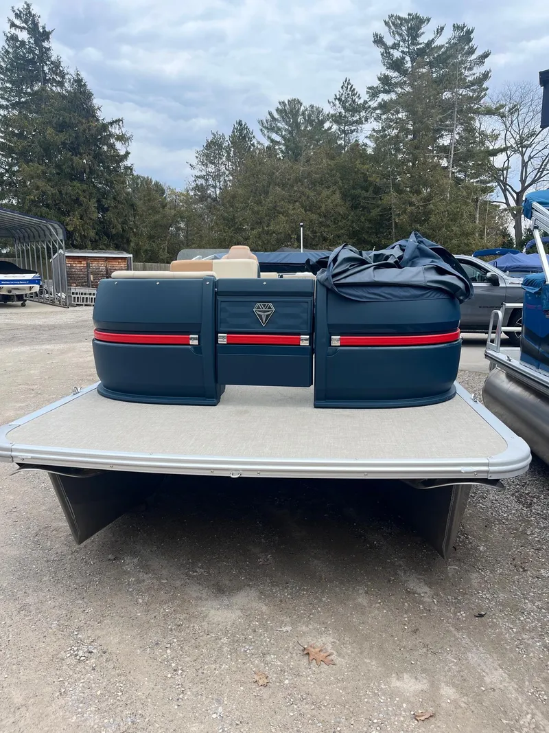 Slide: The Image of 2025 Avalon Aura 21 pontoon boat on a gravel surface, surrounded by trees. - 9