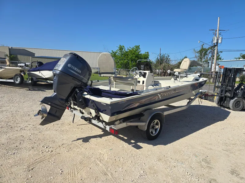 Slide: The Image of 2013 Xpress H20B boat with Yamaha outboard motor on a trailer, parked outdoors. - 4