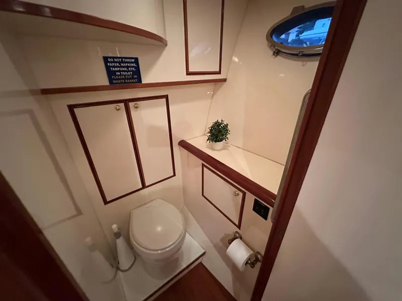 Slide: The Image of Bathroom interior of 1999 Mikelson Long-Range Luxury Sportfish yacht, featuring wood accents and porthole. - 25