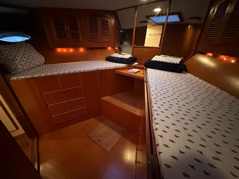 Slide: The Image of 1999 Mikelson Long-Range Luxury Sportfish cabin with twin beds and wooden interior. - 34