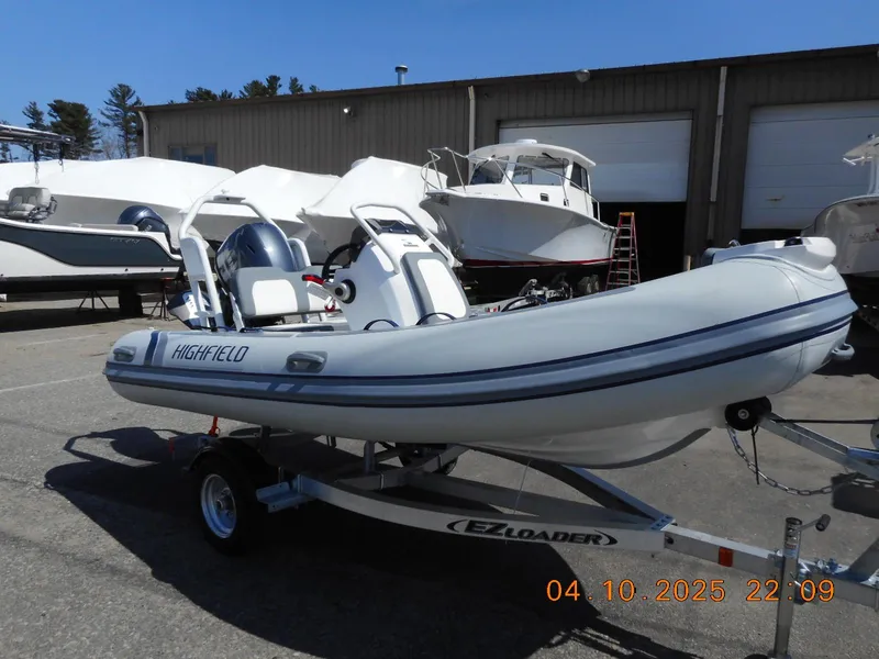 Slide: The Image of 2025 Highfield Classic 400 boat on trailer, parked outdoors near other boats. - 2