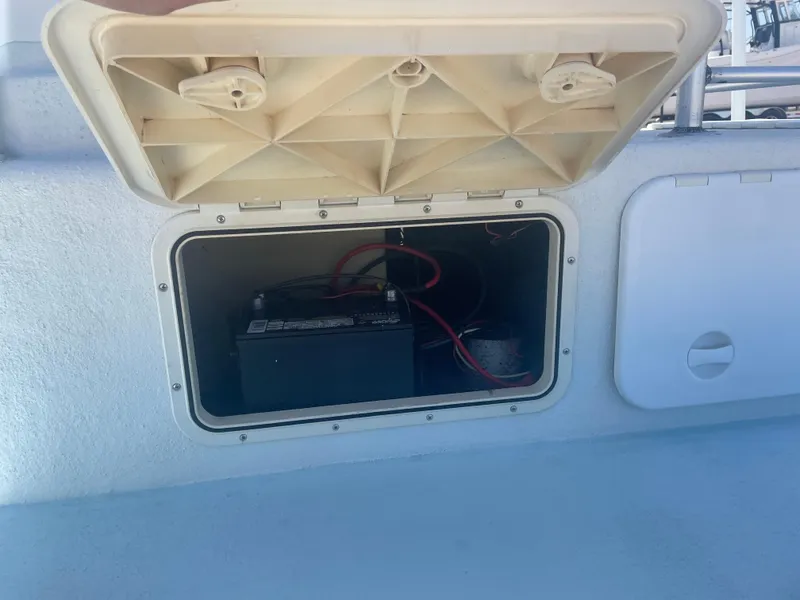 Slide: The Image of Open storage compartment on 2006 Explorer 19 boat, revealing battery and wiring. - 21