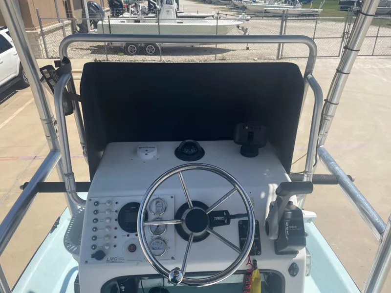 Slide: The Image of 2006 Explorer 19 boat console with steering wheel and controls, parked in a marina. - 22
