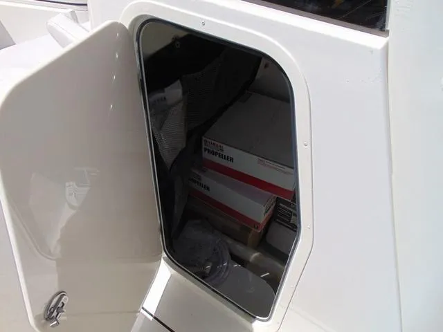Slide: The Image of Open storage compartment on 2025 Parker 2600 CC boat with propeller boxes inside. - 24