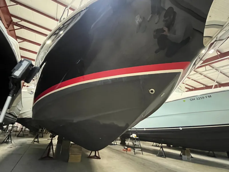 Slide: The Image of 2006 Regal 3360 Window Express boat in storage, featuring a sleek black hull with red stripe. - 2
