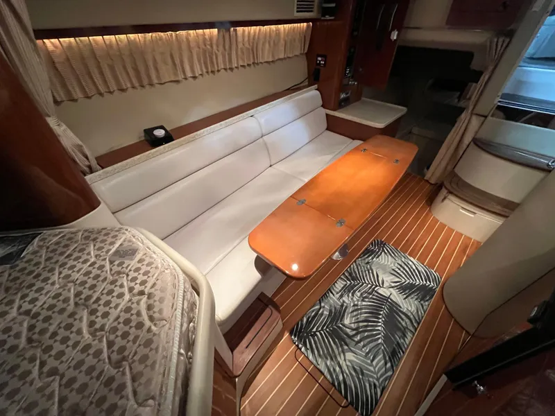 Slide: The Image of 2006 Regal 3360 Window Express interior with white seating, wooden table, and patterned rug. - 9