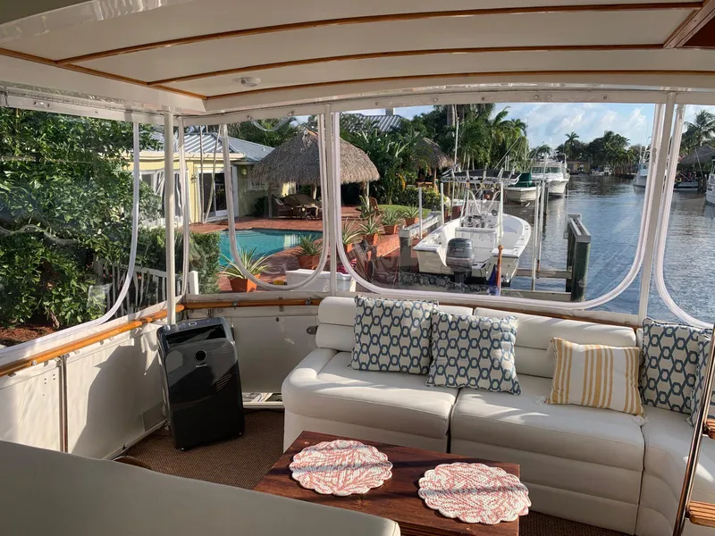 Slide: The Image of 1987 Bertram Motor Yacht interior with white seating, decorative pillows, and marina view. - 2