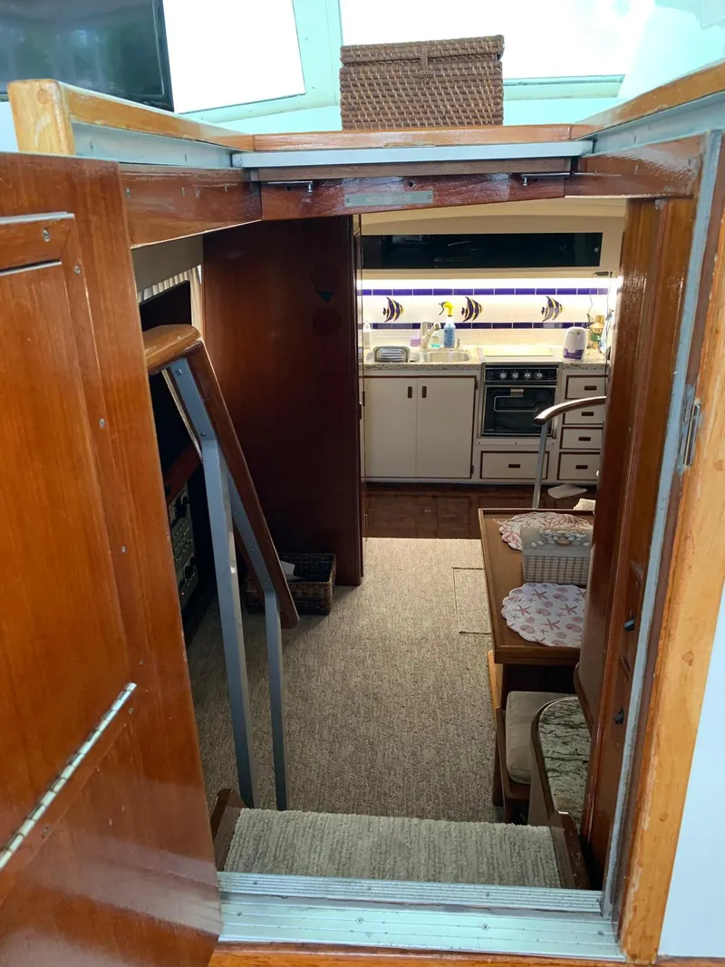 Slide: The Image of 1987 Bertram Motor Yacht interior with wooden finishes, kitchen, and dining area. - 7
