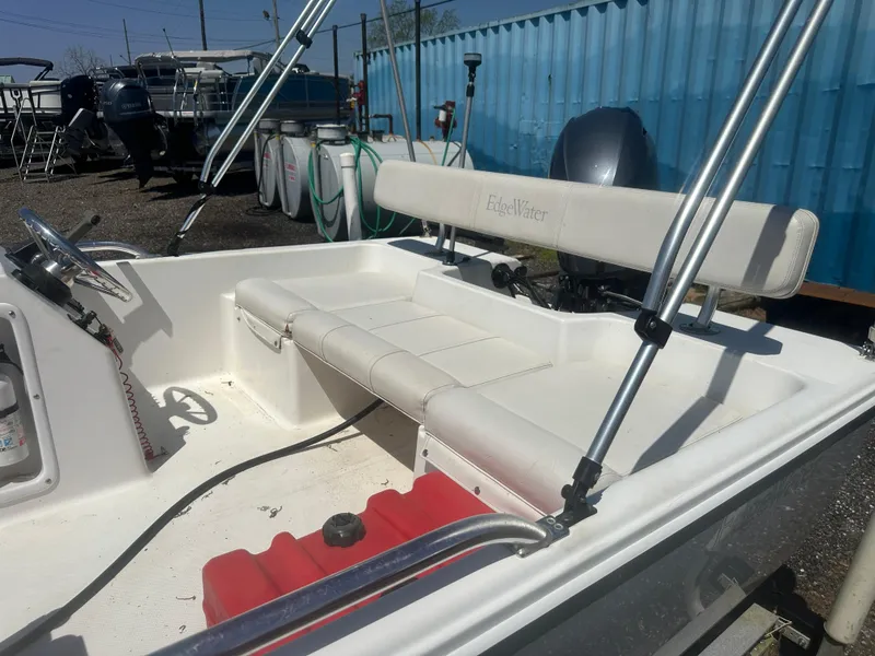 Slide: The Image of 2002 Edgewater 135ST boat interior with seating and steering wheel, docked near blue container. - 13