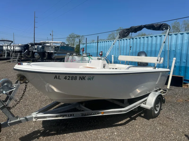 Slide: The Image of 2002 Edgewater 135ST boat on trailer, parked outdoors near blue shipping container. - 9