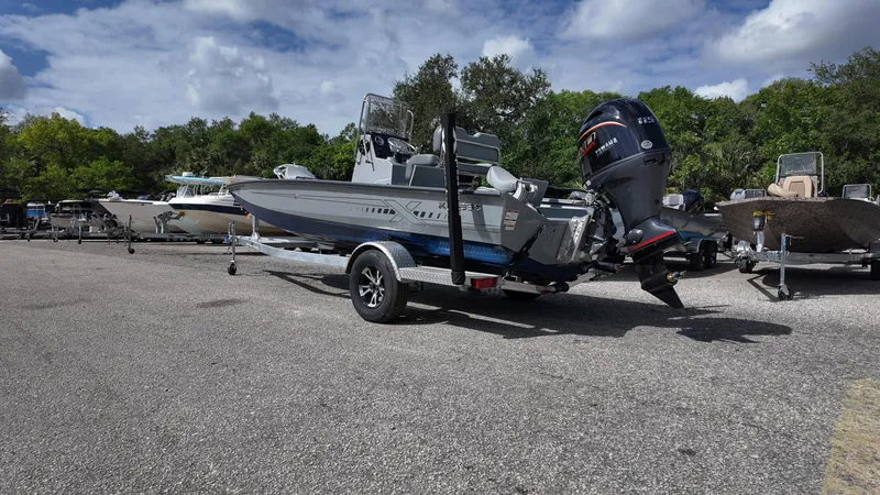 Slide: The Image of 2025 Xpress H20B boat on trailer in parking lot, surrounded by trees and other boats. - 15