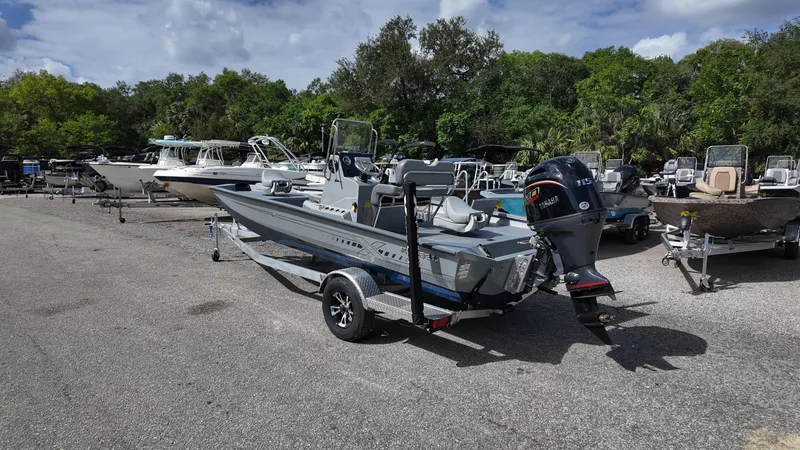 Slide: The Image of 2025 Xpress H20B boat on trailer in outdoor lot, surrounded by trees and other boats. - 16