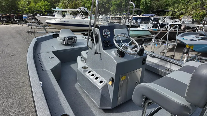 Slide: The Image of 2025 Xpress H20B boat interior with steering console and seating, docked among other boats. - 19
