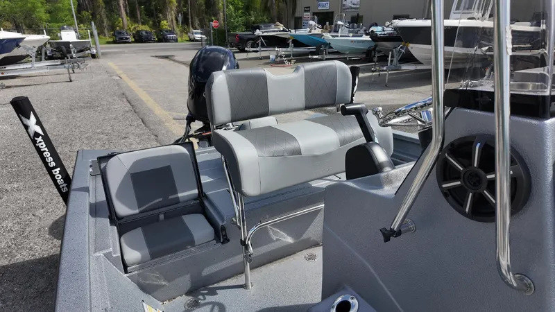 Slide: The Image of 2025 Xpress H20B boat interior with gray seating and steering wheel, parked outdoors. - 26