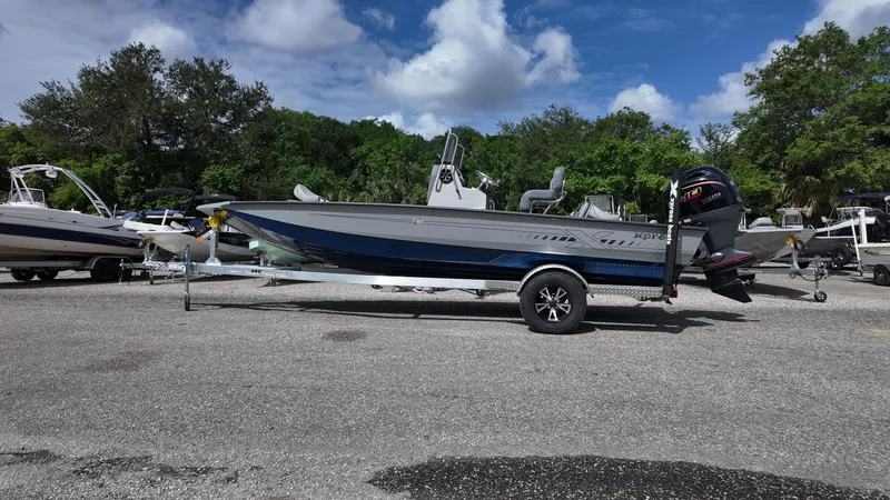 Slide: The Image of 2025 Xpress H20B boat on trailer, parked outdoors under a clear blue sky. - 9