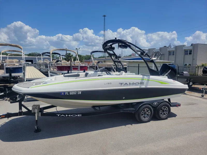 Slide: The Image of 2021 Tahoe 2150 boat on trailer, parked outdoors under a clear blue sky. - 1