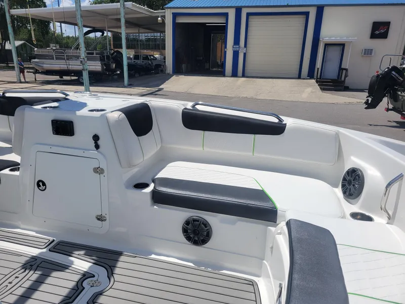 Slide: The Image of 2021 Tahoe 2150 boat interior with seating and speakers, parked near a blue and white building. - 14