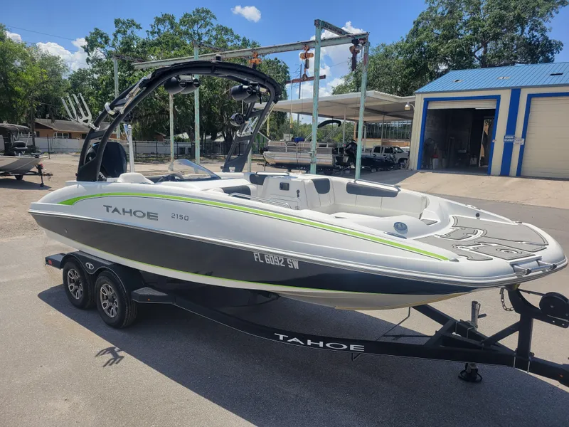 Slide: The Image of 2021 Tahoe 2150 boat on trailer, parked outdoors near a blue-roofed building. - 3
