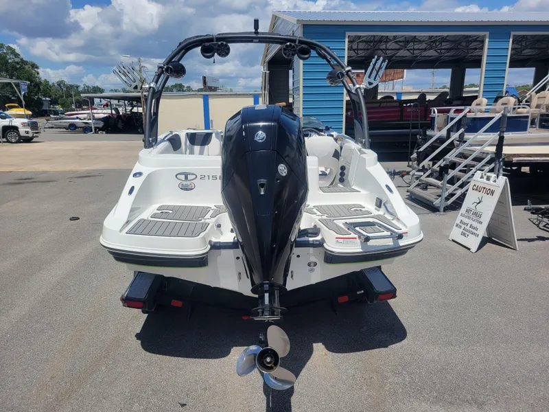 Slide: The Image of 2021 Tahoe 2150 boat with outboard motor, parked outdoors near a blue building. - 5