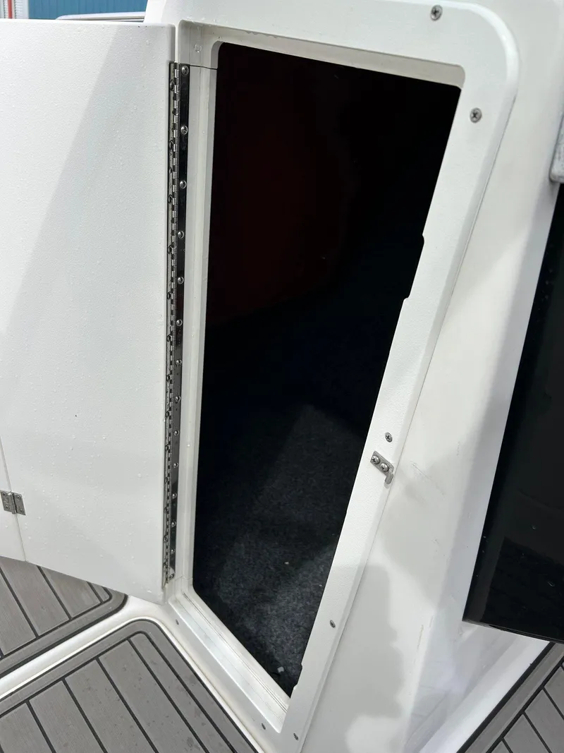 Slide: The Image of 2015 Yamaha Boats 242 Limited S storage compartment with open door. - 11