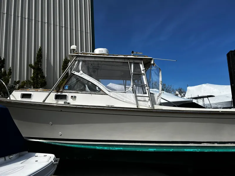 Slide: The Image of 1983 Fortier 26 boat with cabin, docked under clear blue sky. - 0