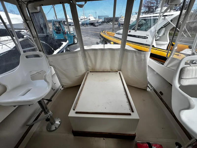 Slide: The Image of 1983 Fortier 26 boat interior with seating and storage, docked alongside other vessels. - 14