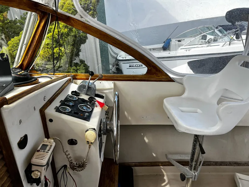 Slide: The Image of Interior of a 1983 Fortier 26 boat showing helm controls and a white captain's chair. - 16