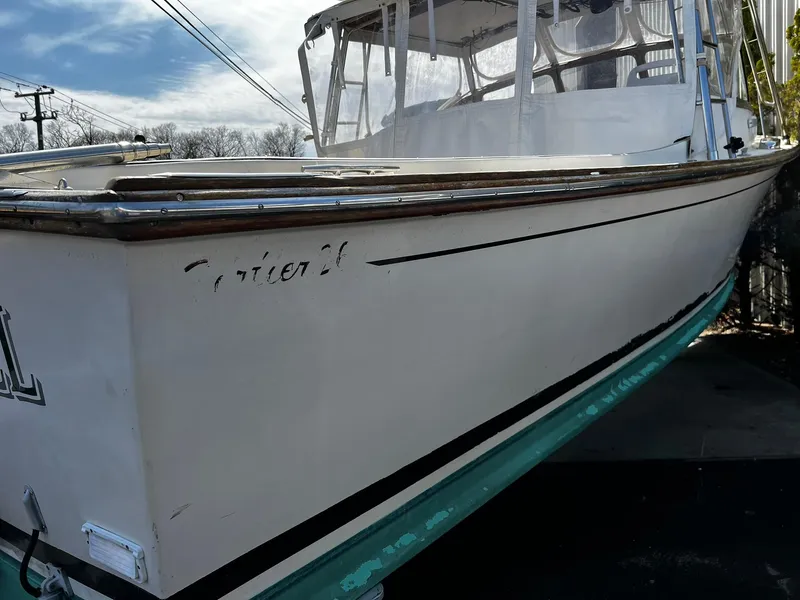 Slide: The Image of 1983 Fortier 26 boat with white hull and canopy, docked outdoors. - 2