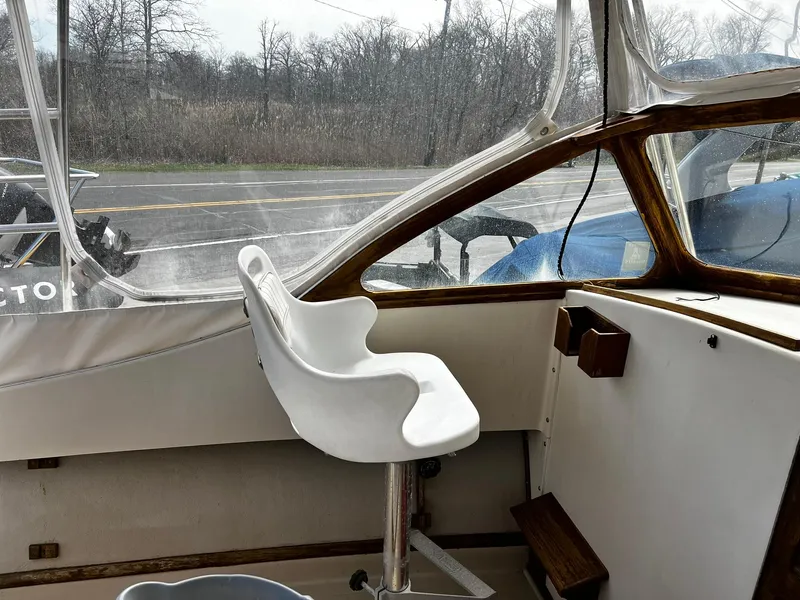Slide: The Image of 1983 Fortier 26 boat interior with white captain's chair and clear windows. - 20