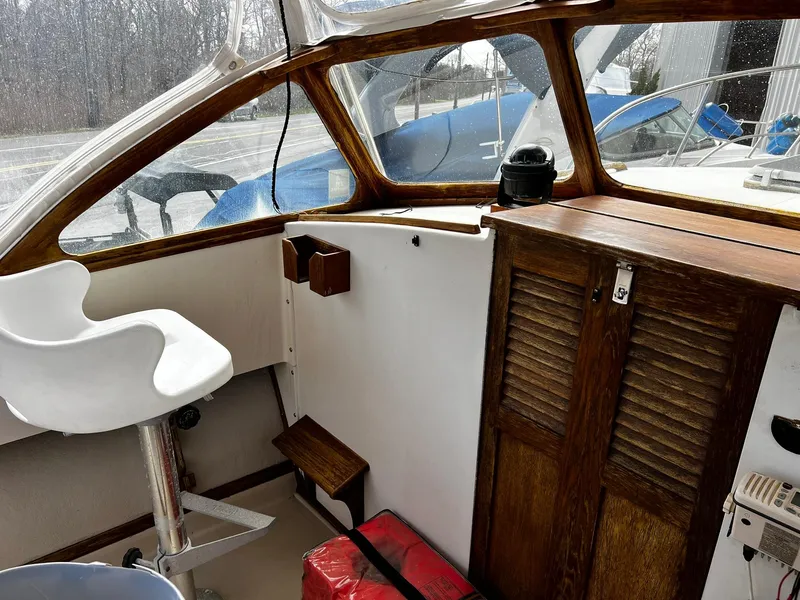 Slide: The Image of 1983 Fortier 26 boat interior with wooden cabinetry and white captain's chair. - 21