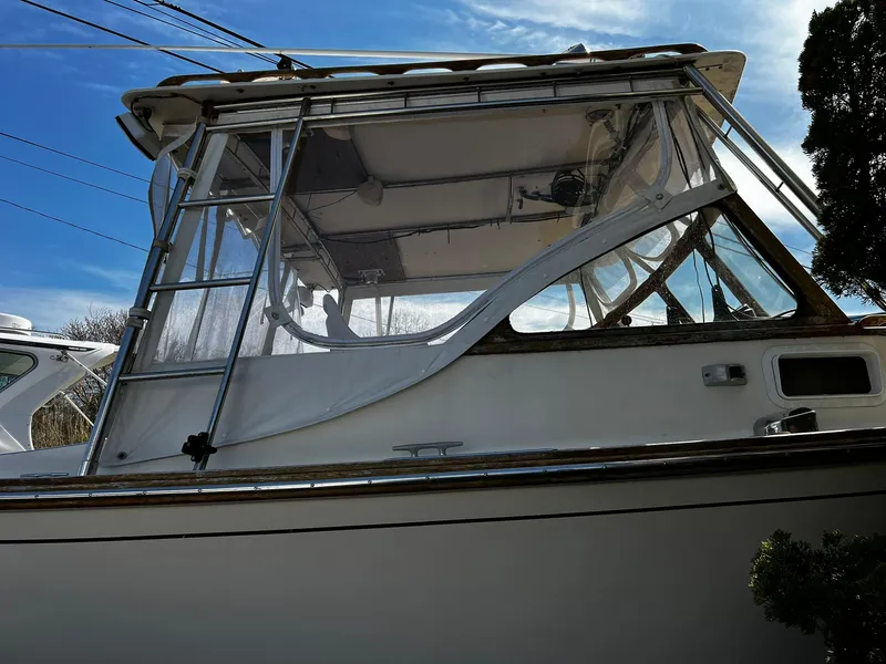 Slide: The Image of 1983 Fortier 26 boat with enclosed cabin, viewed from the side under a clear blue sky. - 3
