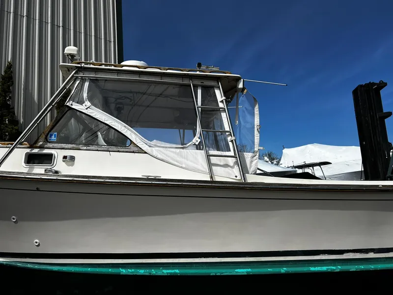 Slide: The Image of 1983 Fortier 26 boat with enclosed cabin, docked under clear blue sky. - 6