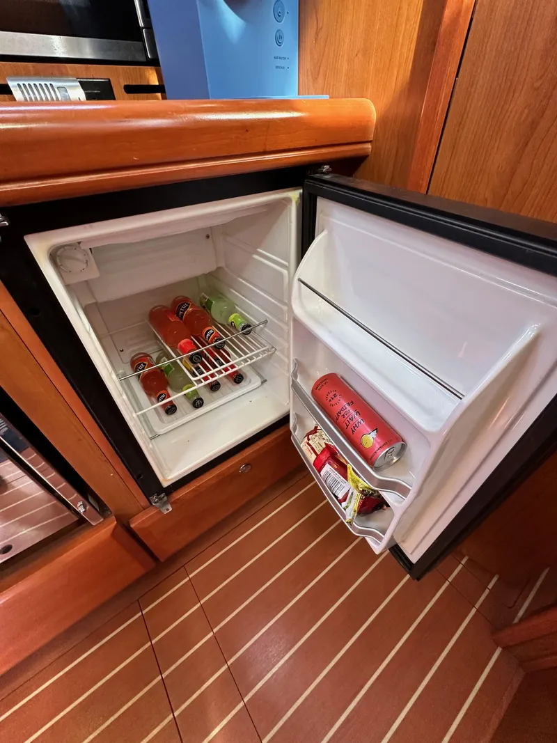 Slide: The Image of Mini fridge in 2008 Hunter 38 yacht, stocked with beverages, open on wooden floor. - 46