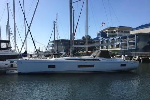 The Image of 2019 Beneteau Oceanis 51.1 yacht docked at a marina, with modern buildings in the background. - 1