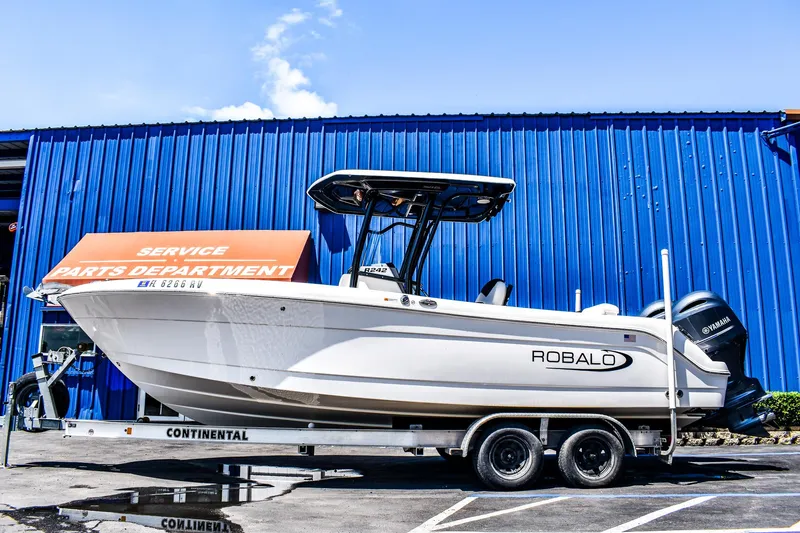 Slide: The Image of 2019 Robalo R242 Center Console boat on trailer, parked near blue building. - 1