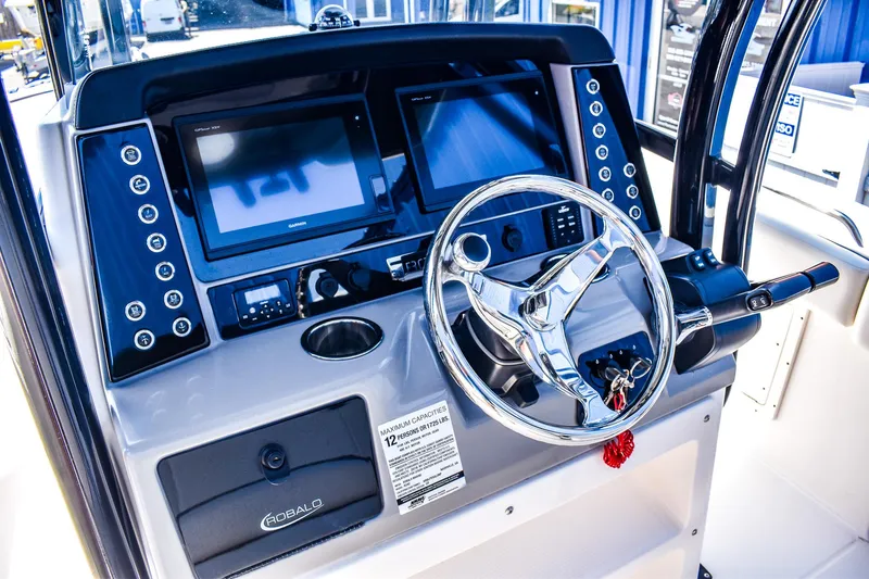 Slide: The Image of 2019 Robalo R242 Center Console boat dashboard with steering wheel and dual displays. - 6