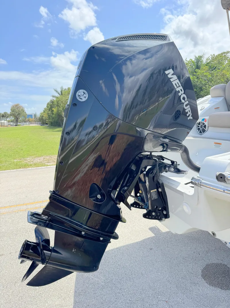 Slide: The Image of 2022 Crownline Eclipse E235 XS with Mercury outboard engine, parked outdoors under a clear sky. - 28